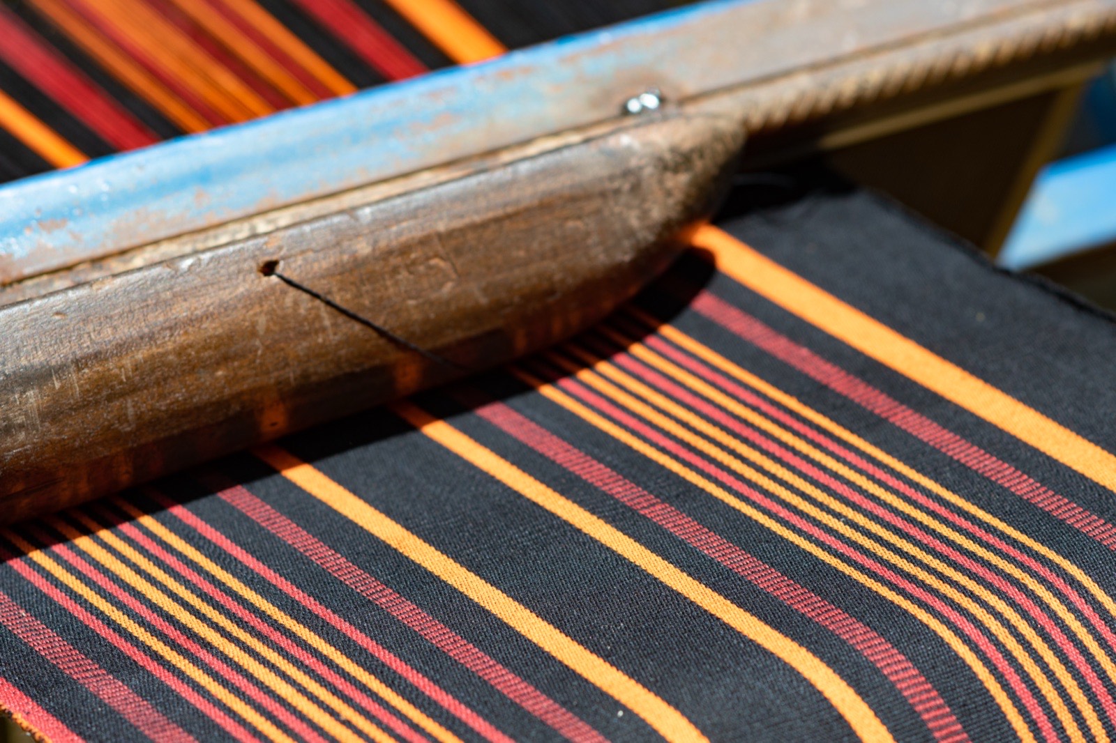 Handwoven striped cotton on a traditional loom in Burkina Faso — warp and weft in black, gold and red